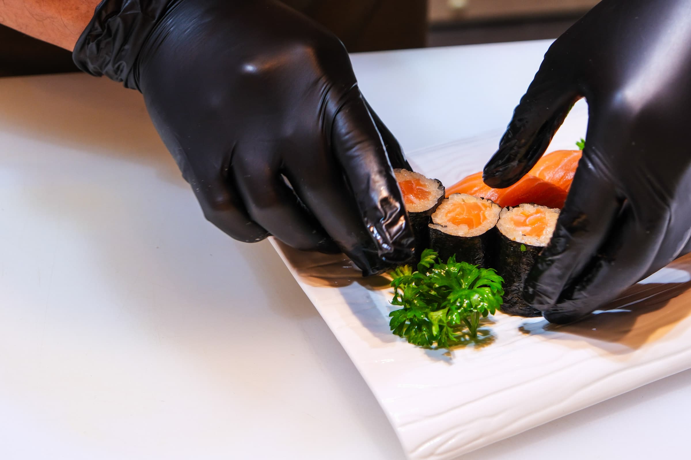 Chef hands carefully arranging sushi on plate